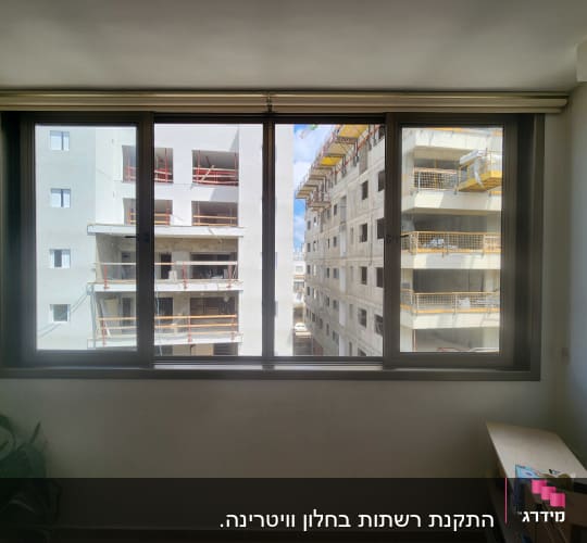 חלון אלומיניום גדול עם נוף לבניינים בבנייה